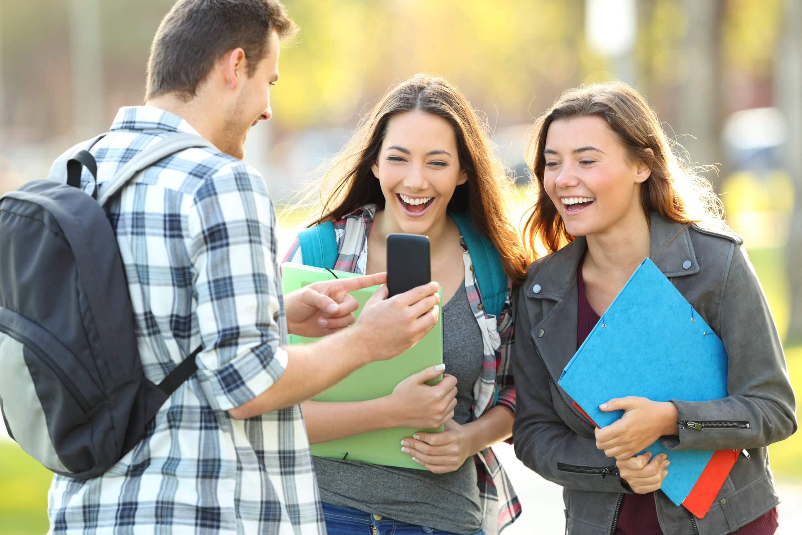 Three Students Sharing Phone Content In A Park